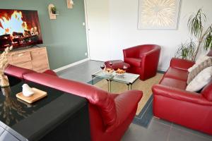 a living room with red chairs and a fireplace at Maison moderne avec spa et jardin sans vis-à-vis, idéal professionnels et familles - L'ÉCRIN BRETON in Vannes