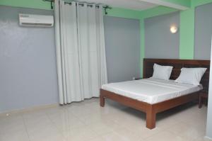 a bedroom with a bed with white sheets and white pillows at Ngueye Hotel in Yaoundé +3 photos