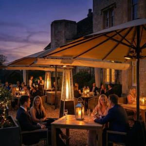 a group of people sitting at a table under an umbrella at Weston Manor Hotel in Bicester