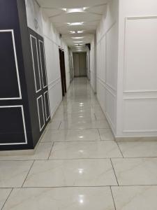 an empty hallway with white walls and a tile floor at hotel apple tree in Bahādurgarh
