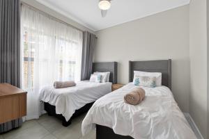 a bedroom with two beds with white sheets and a window at Ballito Hills 830 in Ballito +22 photos