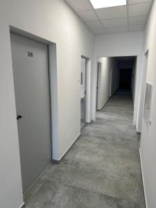 an empty corridor in an office building with white doors at Mieszkateria in Piotrków Trybunalski +1 photo
