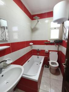 a red and white bathroom with a tub and a toilet at Ibiza beach apartments in Alexandria +18 photos