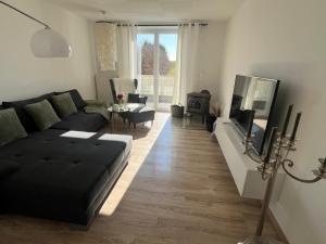 a living room with a black couch and a television at Hochsitz Appartement in Seelitz