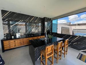 a kitchen with a black counter top and wooden chairs at Espaço completo MOTO GP in Aparecida de Goiânia