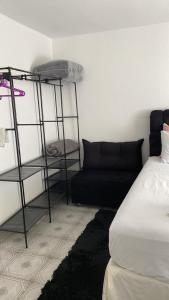 a room with a bed and a black couch at Casa no Roteiro do Vinho - Casa 02 in São Roque