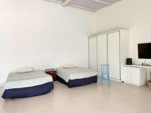 two beds in a room with a tv and a chair at Espaço completo MOTO GP in Aparecida de Goiânia