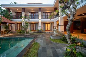 a villa with a swimming pool in front of a house at Yoga Sri Ubud Hotel & Spa in Ubud