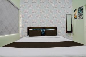 a bedroom with a large bed with white sheets and floral wallpaper at Hotel O Dhauli Inn in Pānchagān +28 photos