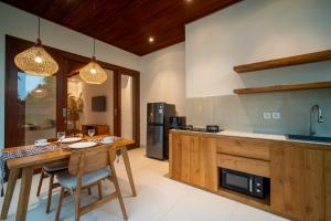 a kitchen with a wooden table with chairs and a counter at Yoga Sri Ubud Hotel & Spa in Ubud