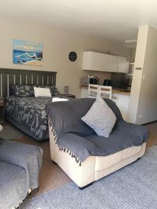 a bedroom with a couch and a bed and a kitchen at 5 Bayview Gonubie Seaside in Gonubie