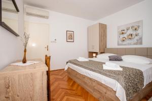 a bedroom with a bed and a vase on a table at Apartments Dionis in Rab +36 photos
