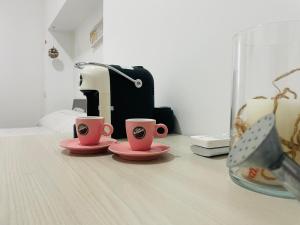 two pink coffee cups sitting on a table with a toaster at Dolce VillaCastelli in Villa Castelli