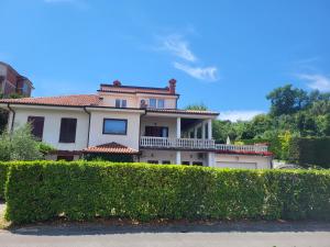 a large white house behind a green hedge at Apartmaji Tim in Izola