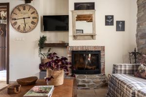a living room with a fireplace and a clock on the wall at Casa Rural Tío Conejo in San Román de Cameros