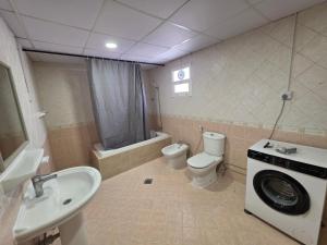 a bathroom with a toilet sink and a washing machine at Crescent by Oasis in Abu Dhabi