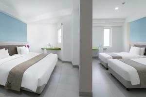 two beds in a room with white walls and windows at JP Hotel Pluit Jakarta by LIFE in Jakarta