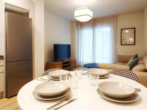a kitchen and living room with a table with plates and silverware at Apt 2 hab Catedral II, Terraza, Parking, Centro in Valladolid