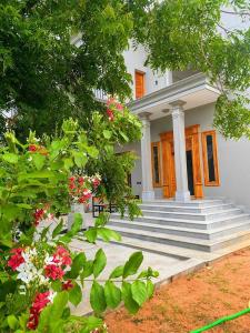 a white house with stairs and flowers in front of it at Desert Beach House with swimming pool in Kuilapayam
