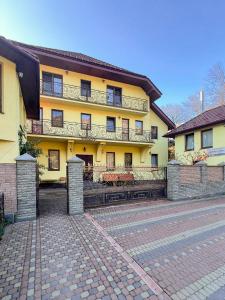 a large yellow building with a brick driveway at Садиба Буркут in Kvasy