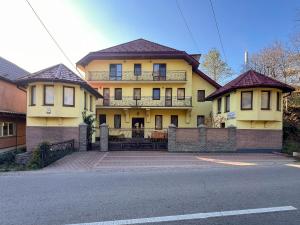 a large yellow house with a balcony on a street at Садиба Буркут in Kvasy