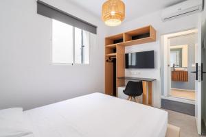 a bedroom with a white bed and a window at Tiendas 26 in Almería