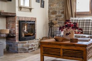 a living room with a stone fireplace and a coffee table at Casa Rural Tío Conejo in San Román de Cameros