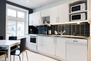 a kitchen with white cabinets and a table with chairs at Trossö Vandrarhem in Karlskrona