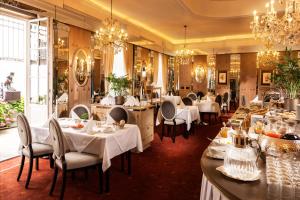 a restaurant with white tables and chairs and chandeliers at Hotel Bristol Salzburg in Salzburg +63 photos
