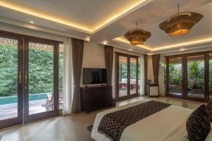 a bedroom with a bed and a tv and a pool at Aksmi Suites & Villas in Bedahulu