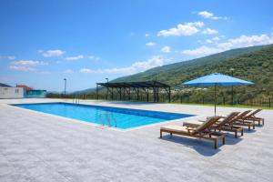 a swimming pool with chairs and an umbrella at Colorato Quba in Qırmızı Qǝsǝbǝ