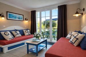 a living room with a red couch and a table at LocaLise - Maison E4 au Guilvinec - A 20m de la mer avec jardin et piscine - Tout à pied, plages, port, centre, commerces, marché - Wifi inclus - Linge de lit inclus - Animaux bienvenus in Le Guilvinec