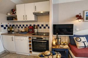 a small kitchen with white cabinets and a sink at LocaLise - Maison E4 au Guilvinec - A 20m de la mer avec jardin et piscine - Tout à pied, plages, port, centre, commerces, marché - Wifi inclus - Linge de lit inclus - Animaux bienvenus in Le Guilvinec +47 photos