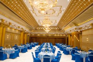 a banquet hall with blue tables and chairs and a chandelier at The Royal Bihar in Patna +65 photos