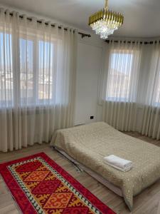 a bedroom with a bed and a chandelier and windows at Guest house Sayak in Bokonbayevo