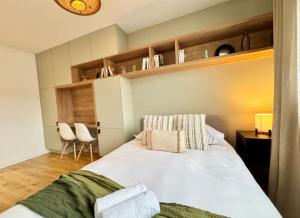 a bedroom with a large white bed with two chairs at La Maison Contemporaine, Luxe et Elégance aux portes de Rennes in Cesson-Sévigné