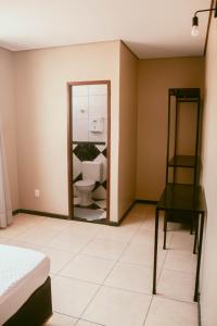 a bedroom with a mirror and a bed and a chair at Kitnet em Betim no centro in Betim