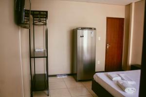 a room with a refrigerator and a bed and a television at Kitnet em Betim no centro in Betim