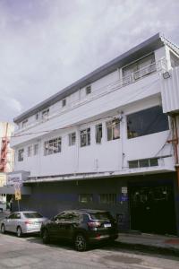 a white building with cars parked in front of it at Kitnet em Betim no centro in Betim