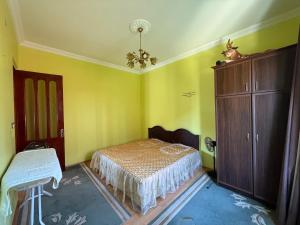a bedroom with yellow walls and a bed and a cabinet at The Bondo's Villa in Kobuleti