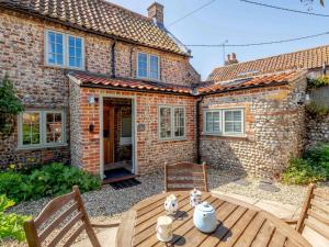 a patio with a wooden table in front of a brick house at 1 Bed in Holt oc-78233 in Cley next the Sea +10 photos