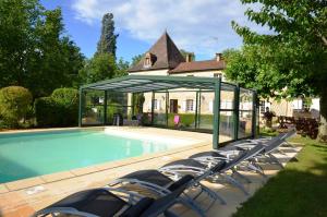 a group of chairs sitting next to a swimming pool at Le Logis du Port in Domme