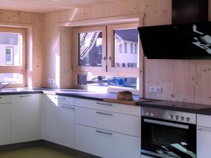 a kitchen with white cabinets and black counter tops at Saunaloft Schwarzwald - privater 45qm Saunabereich - großzügige Räume mit viel Ruhe in Gemeinde Aichhalden