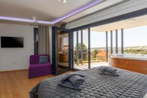 a bedroom with a large bed and a purple chair at Villa Bellavista in Medulin +183 photos