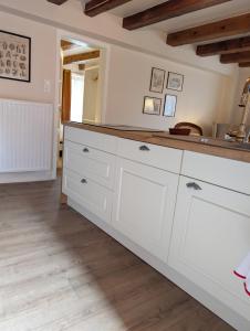a kitchen with white cabinets and a wooden floor at Maison Mycélia in Buhl