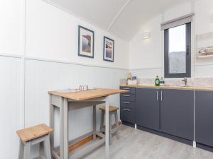 a kitchen with blue cabinets and a wooden table at Shepherds Hut - Uk49096 in Inchnadamph