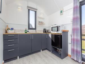 a kitchen with grey cabinets and a microwave at Shepherds Hut - Uk49096 in Inchnadamph
