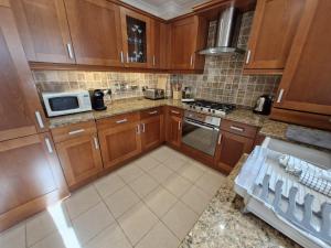 a kitchen with wooden cabinets and a microwave at Broadstairs Hideaway W Parking and Mins to Beach in Broadstairs