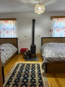 a bedroom with two beds and a wood stove at Florija’s Guesthouse in Dardhë
