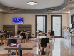 a restaurant with tables and chairs and a flat screen tv at Hotel Guerro in Castelvetro di Modena